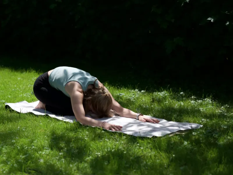 Sanfte Kindhaltung auf der Yogamatte im Grünen – Yoga für Anfänger