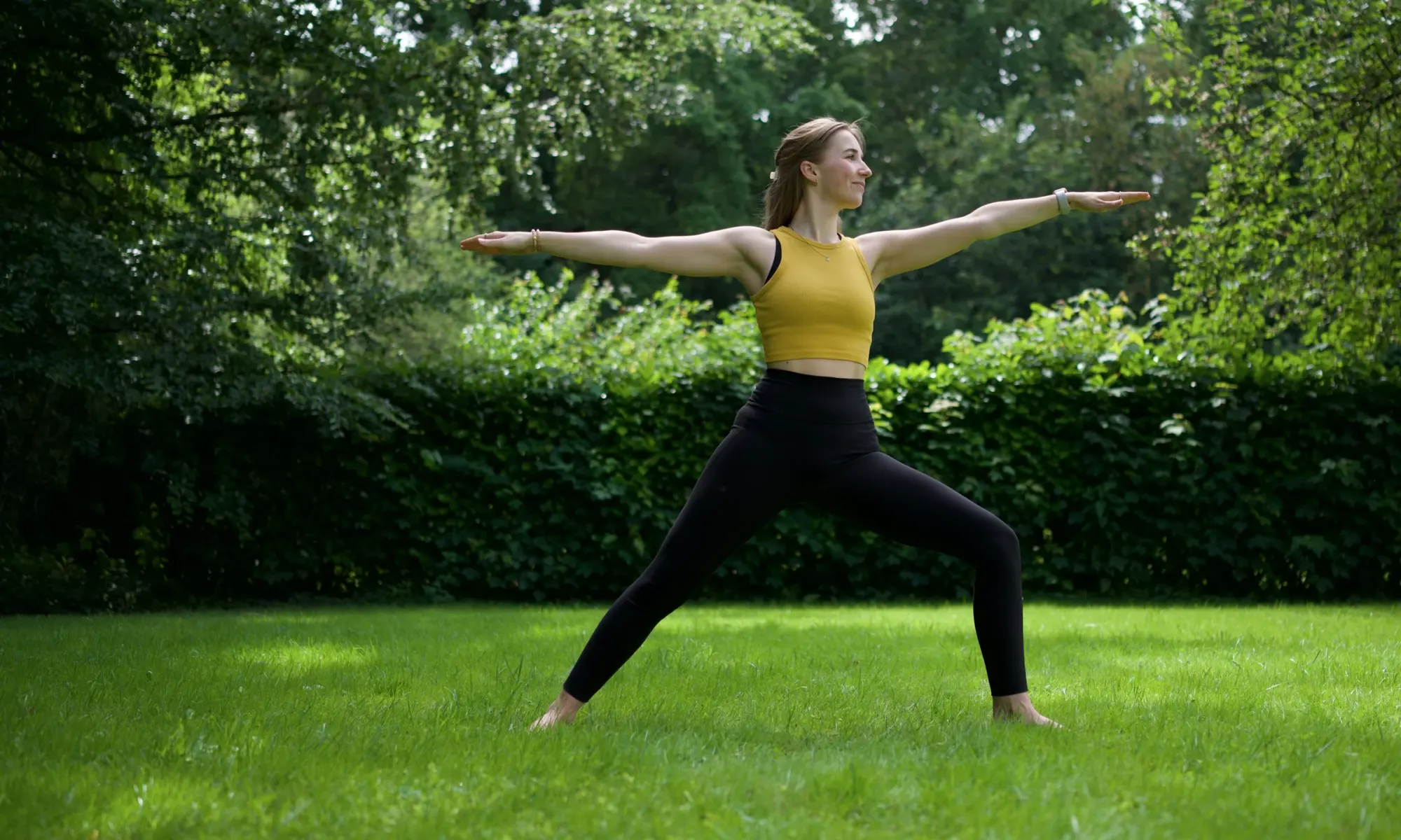 Sara Felsberg in der Krieger-Pose auf einer Wiese in Dormagen – Yoga im Freien